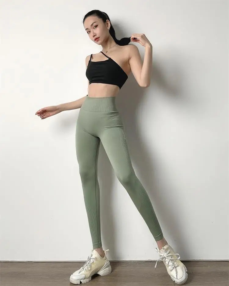 KiKis High Waist Push Up Seamless Leggings in sage green worn with black crop top and white sneakers