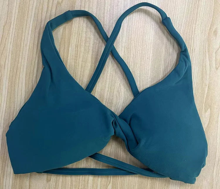 KiKis padded front twist sports bra in teal with crossed back straps and smooth fabric