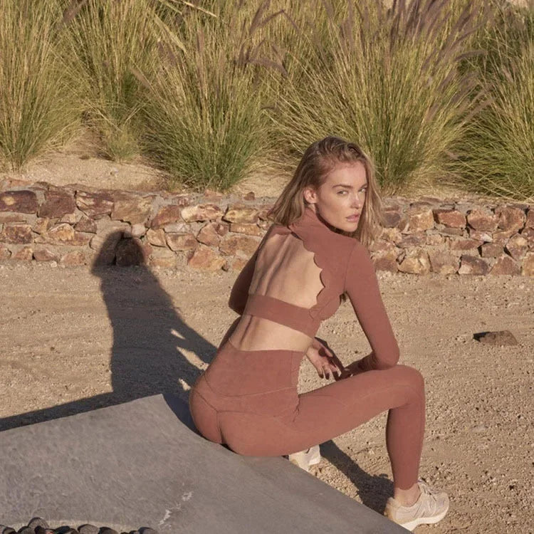 Woman wearing KiKis long sleeve lace back yoga top in brown, sitting outdoors on a yoga mat