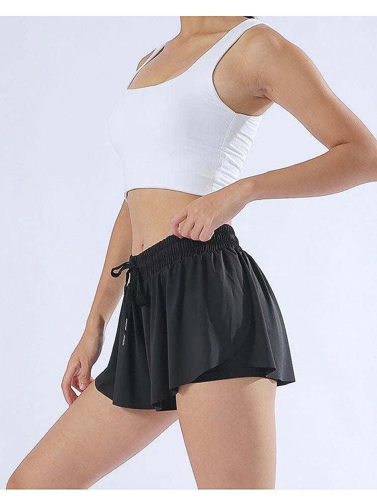 KiKis black yoga running skirt shorts for women with drawstring waistband modeled with white crop top