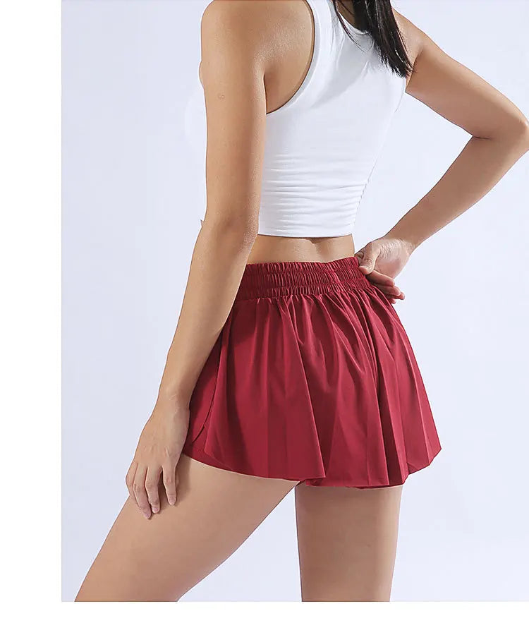 KiKis red yoga running skirt shorts for women with elastic waistband worn by a woman in white crop top