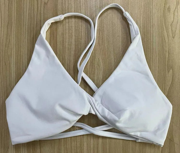 White padded front twist sports bra by KiKis with adjustable straps on wooden surface