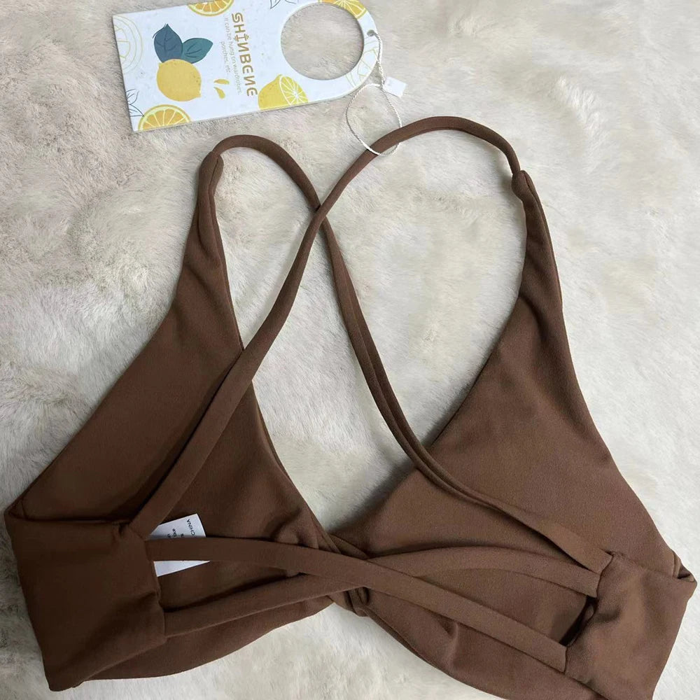 KiKis brown padded front twist sports bra with adjustable straps laid on a light fur background