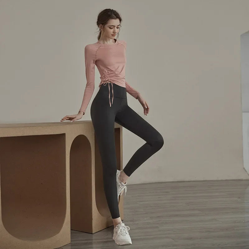 Woman wearing KiKis women's long sleeve yoga top in dusty pink with side drawstring detail