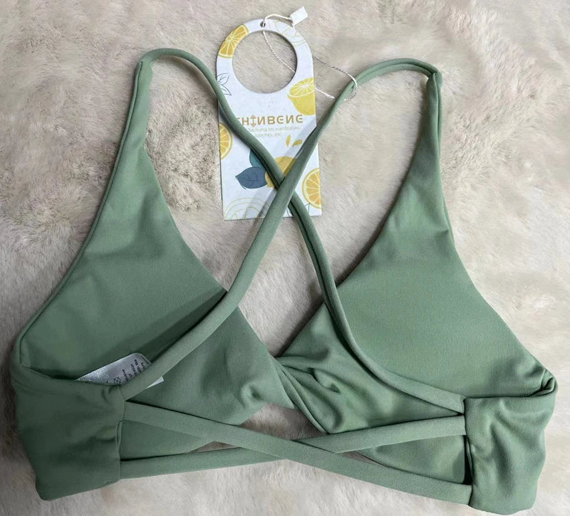 KiKis green padded front twist sports bra with crisscross straps on soft surface