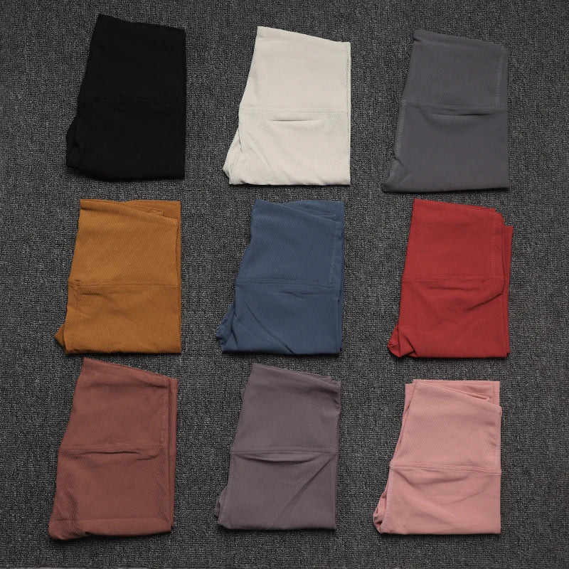Nine pairs of Women's High Waist Cycling Shorts SOISOU Rib Fabric in various colors neatly folded on a gray surface