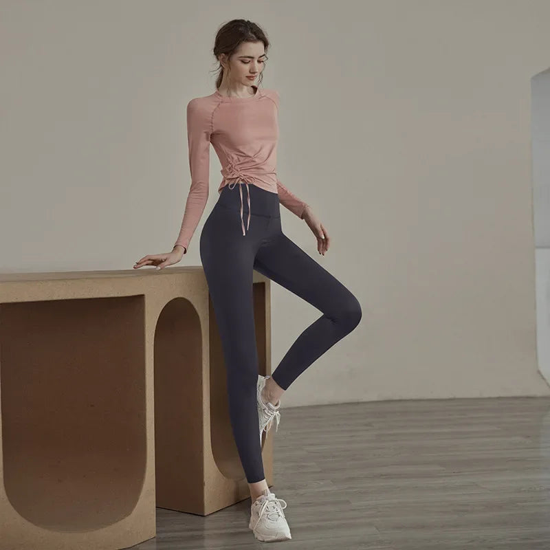 KiKis women's long sleeve yoga top in pink with ruched side detailing worn with navy leggings