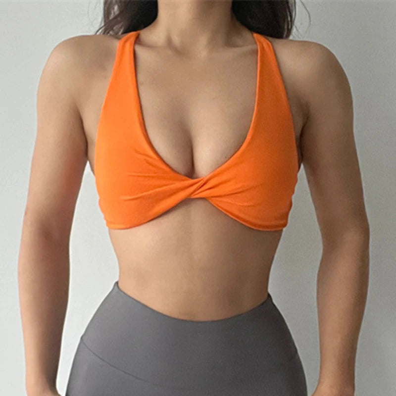 KiKis orange padded front twist sports bra worn with high-waisted gray leggings