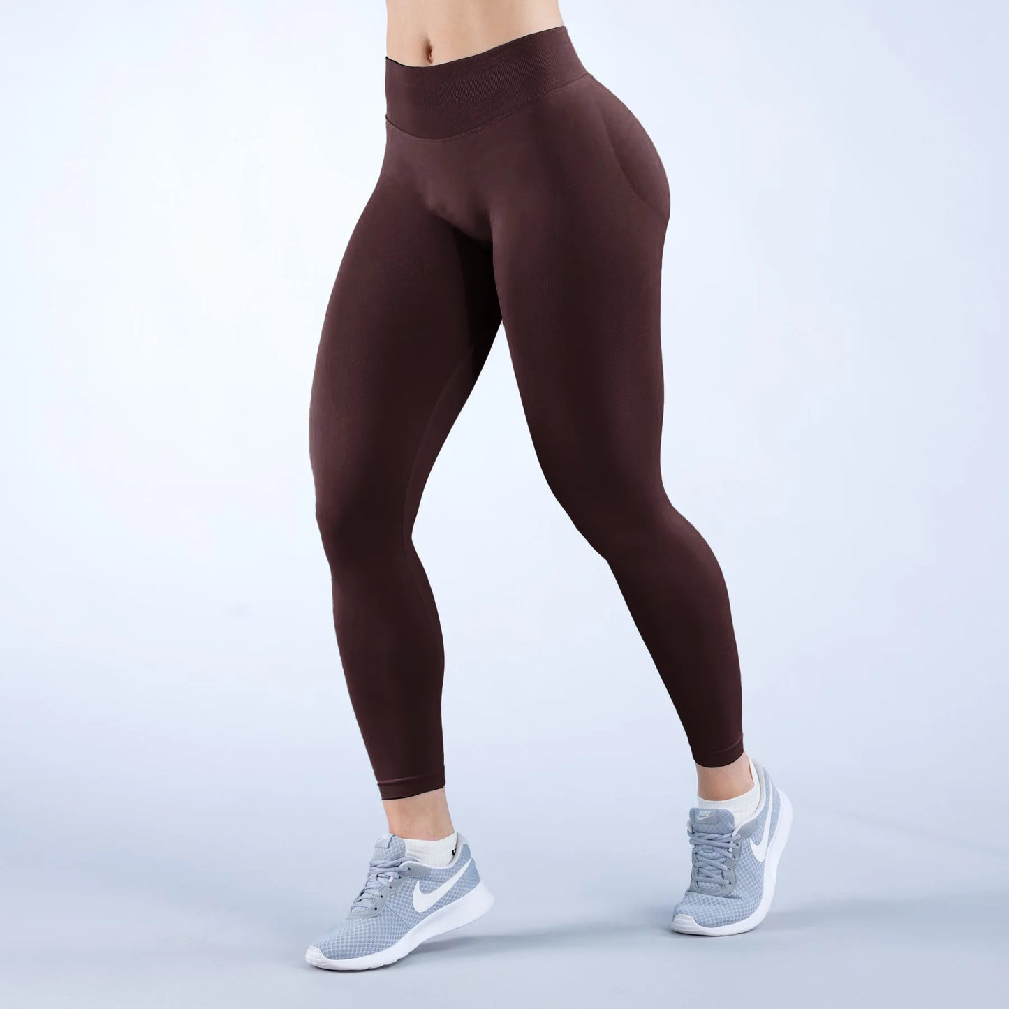 KiKis high-waisted seamless sports leggings in dark brown worn with gray athletic shoes