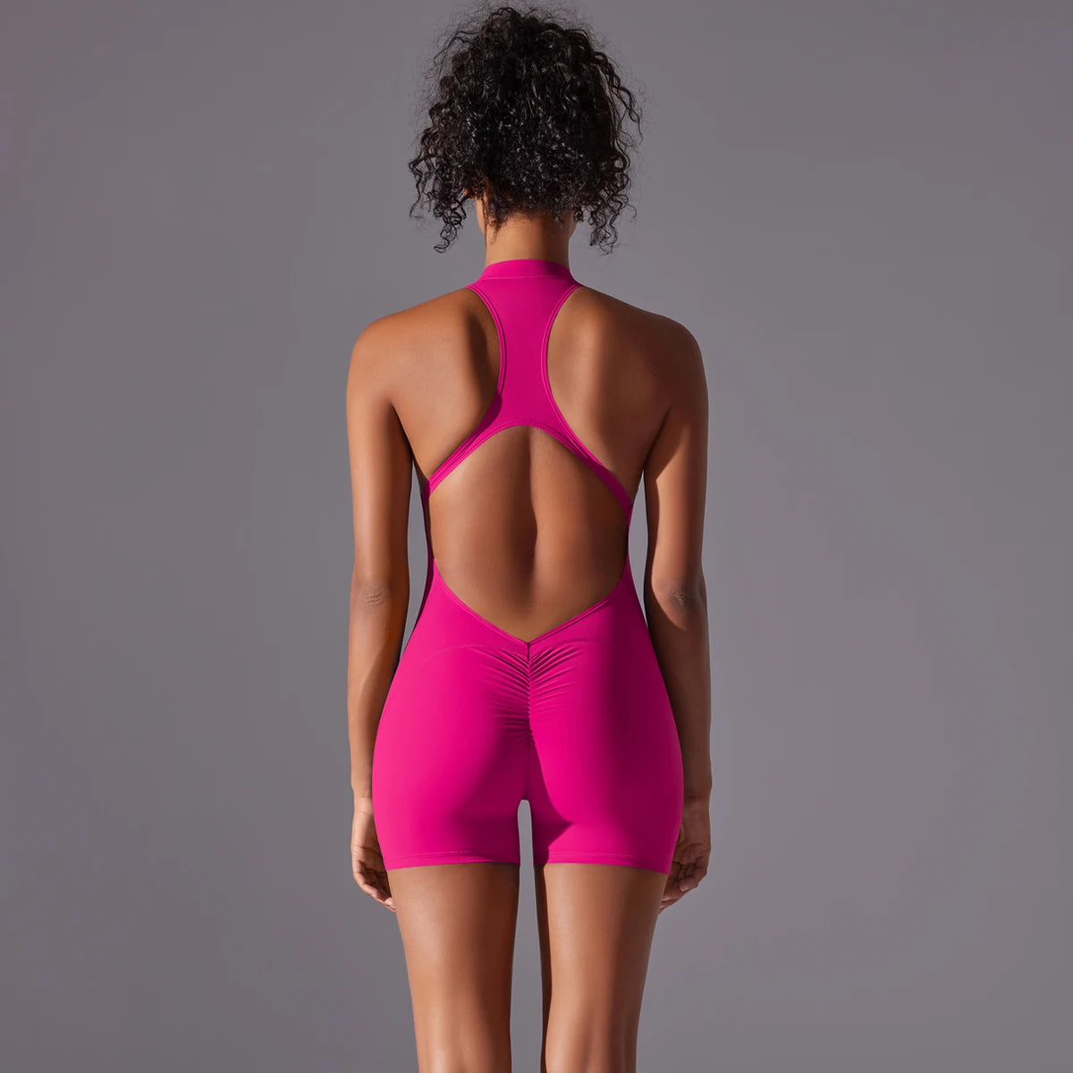 KiKis bright pink backless gym bodysuit for women with racerback design and fitted shorts