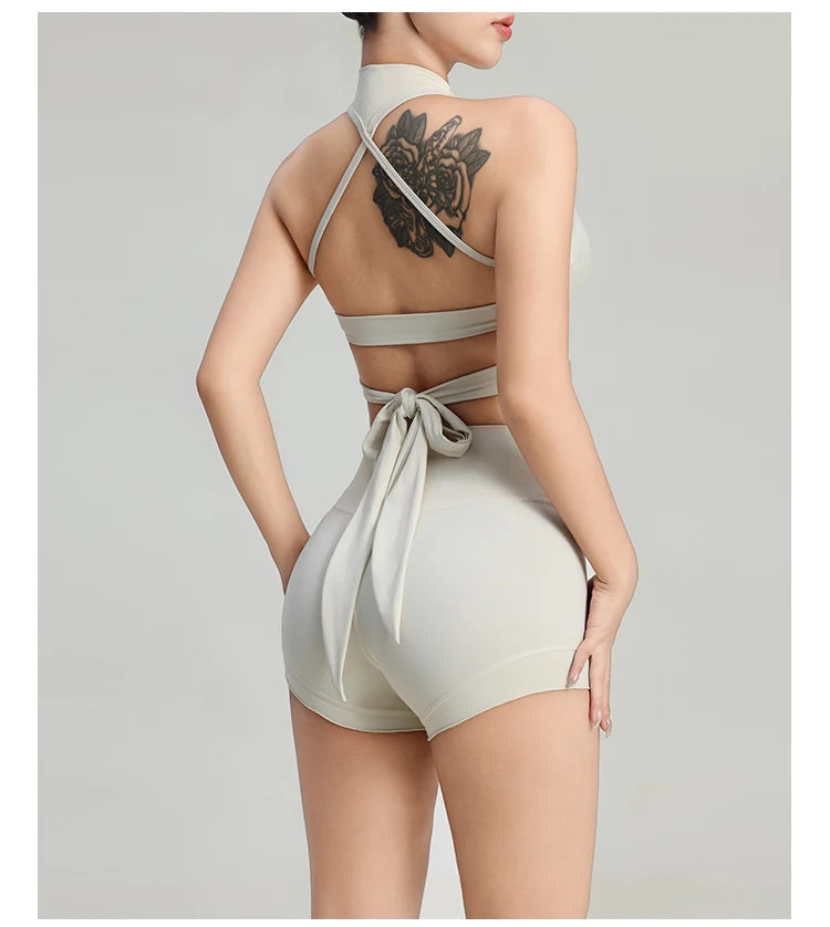Back view of woman wearing comfortable workout tank tops for women by KiKis in light gray with crisscross straps and tie detail