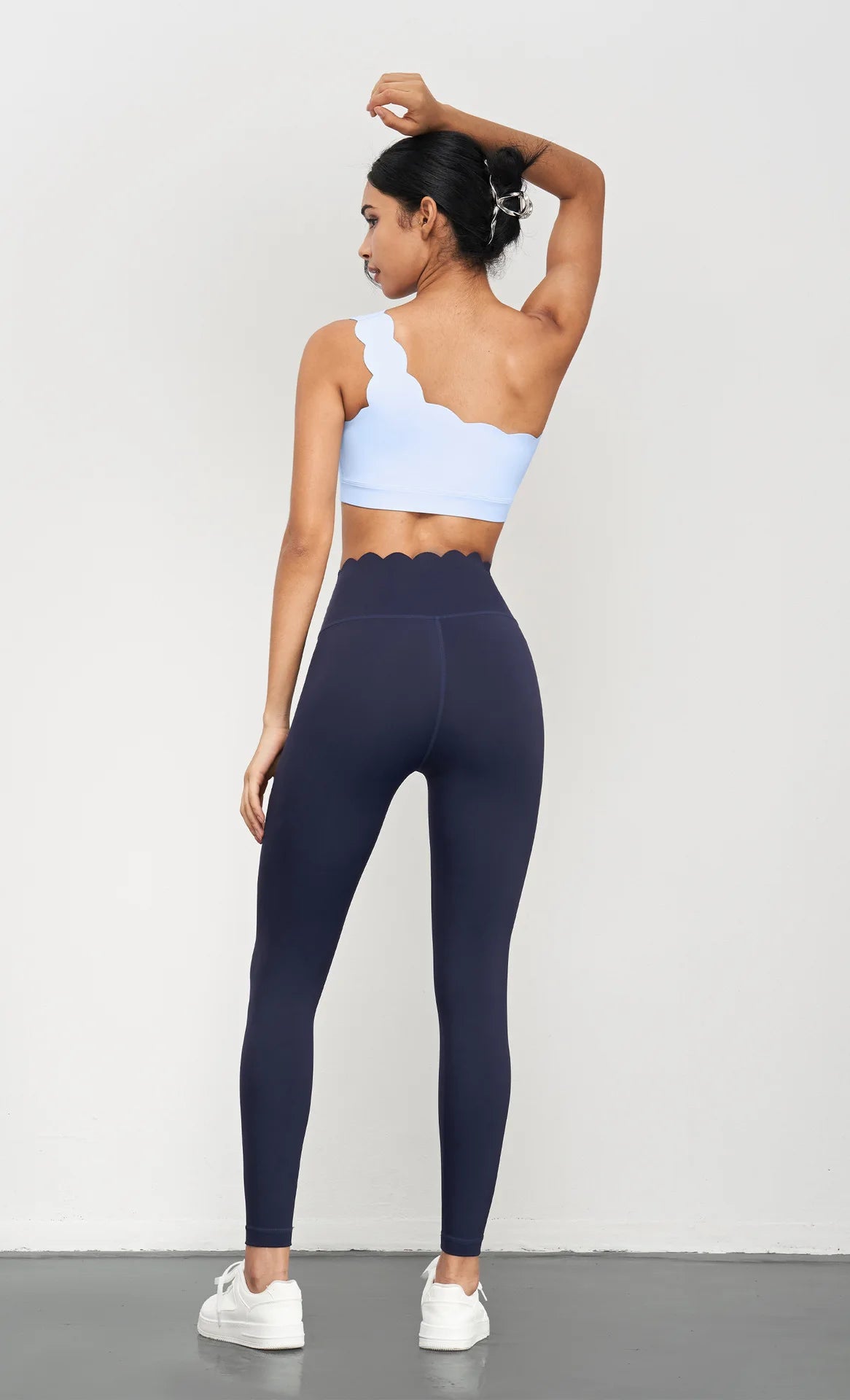 Back view of woman wearing KiKis Women Seamless Lotus Arc Yoga Pants in navy with scalloped waistband