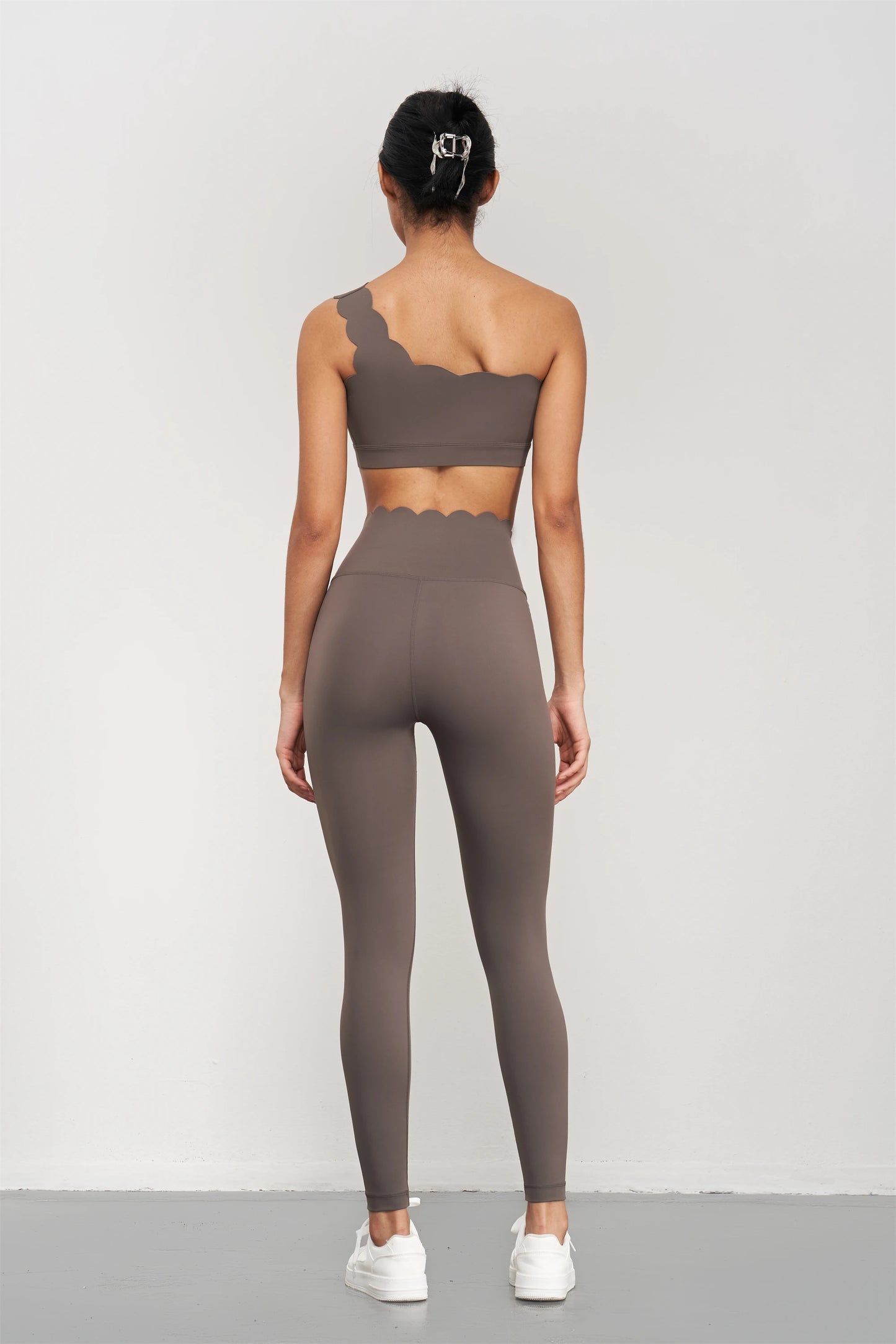Woman wearing Women Seamless Lotus Arc Yoga Pants in brown with matching one-shoulder top from back view