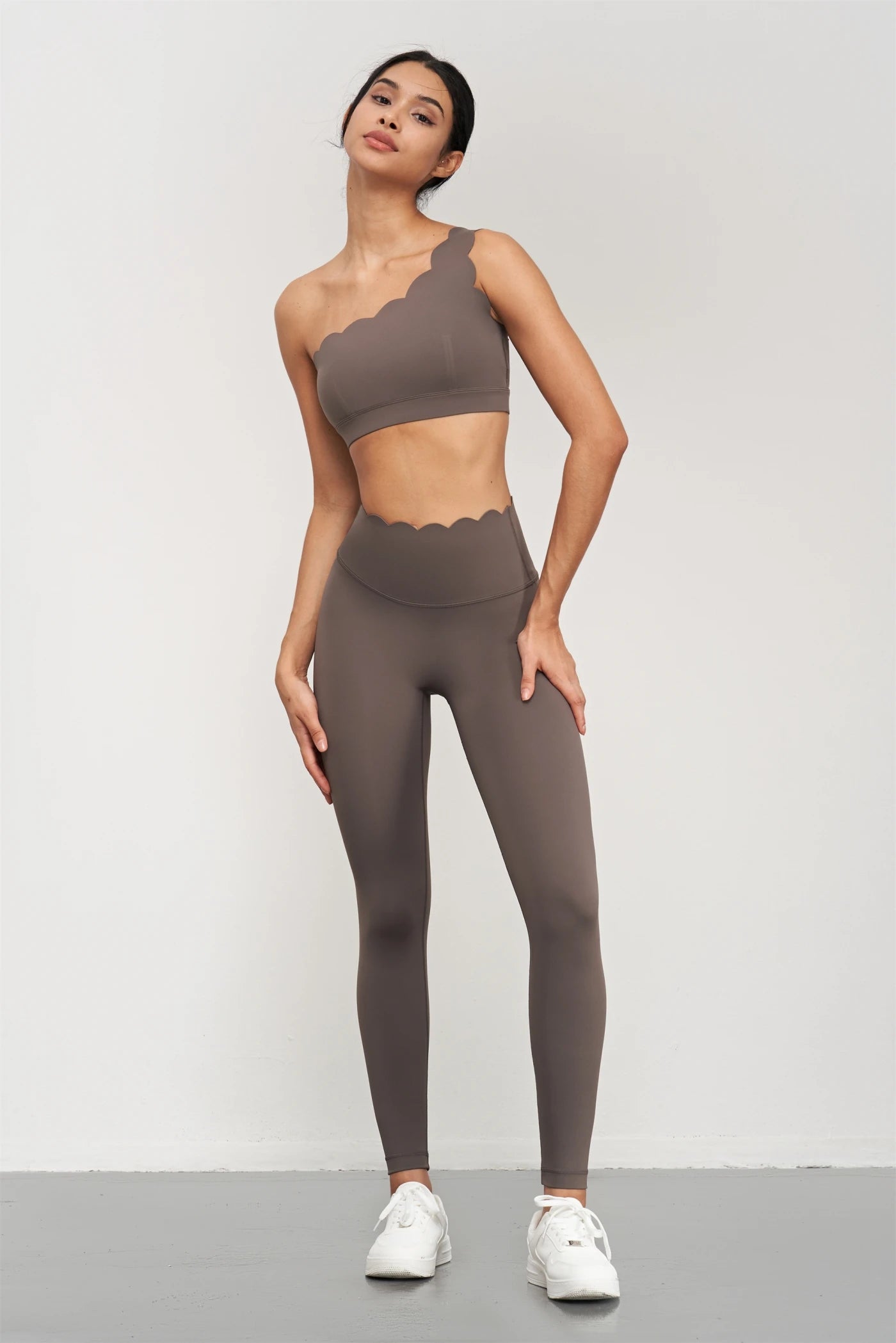 Woman wearing KiKis Women Seamless Lotus Arc Yoga Pants and matching one-shoulder top in brown