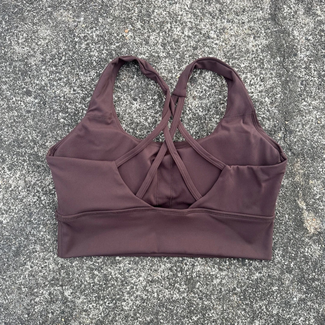 KiKis brown cross back sports bra for women laid flat on stone surface