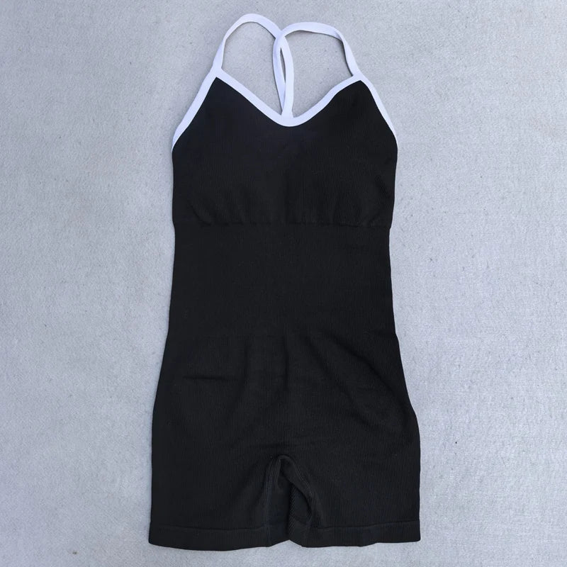 KiKis black cross back strappy jumpsuit with white straps laid flat on a gray surface