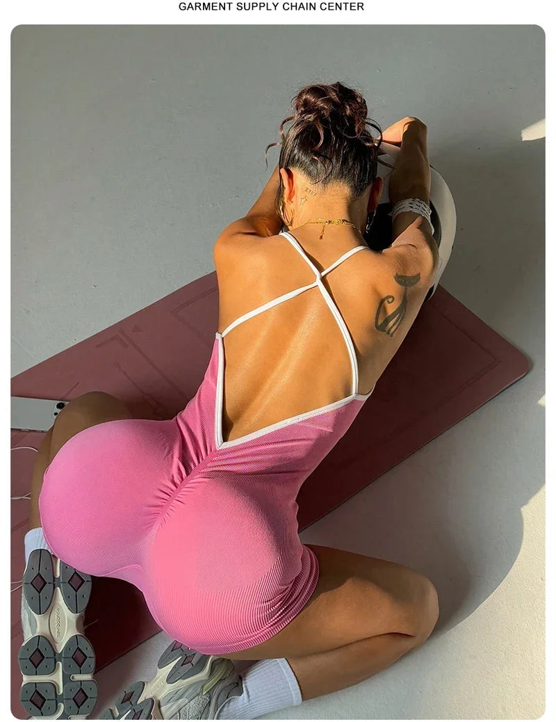 KiKis pink cross back strappy jumpsuit worn by a woman sitting on a yoga mat with sporty sneakers