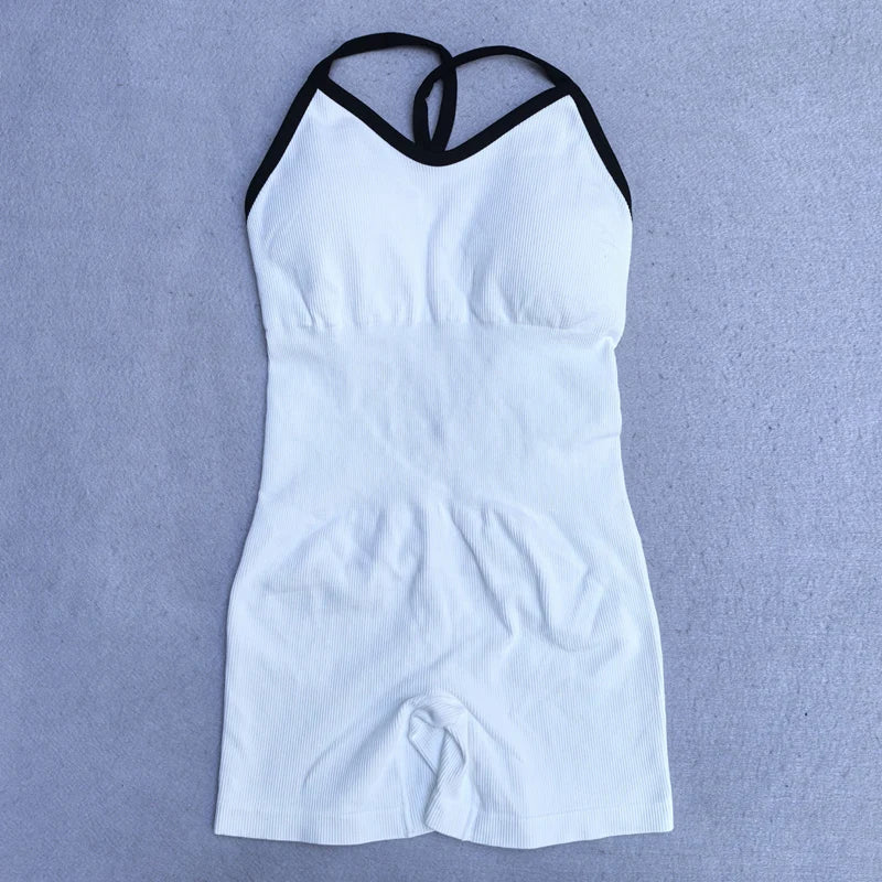 White cross back strappy jumpsuit with black trim by KiKis laid flat on a grey surface