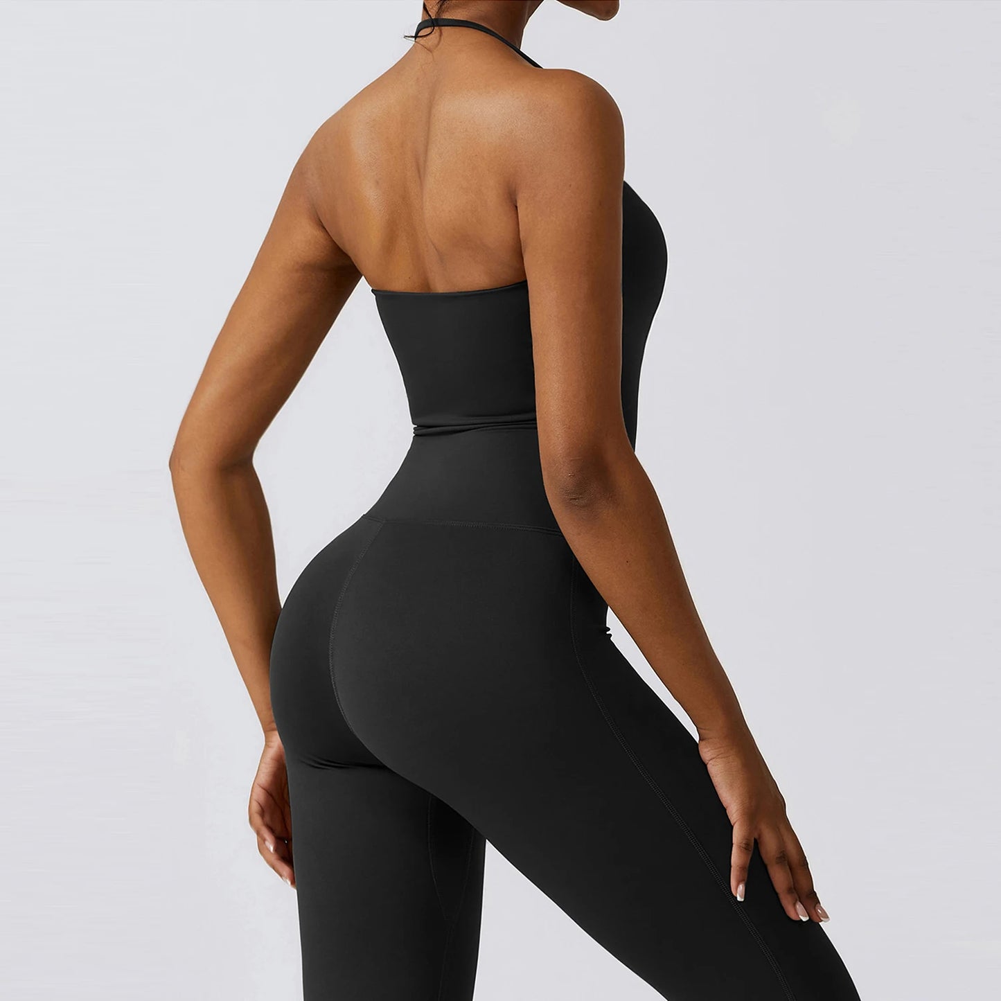 Black one piece yoga suit for women by KiKis showing back and side fit on model