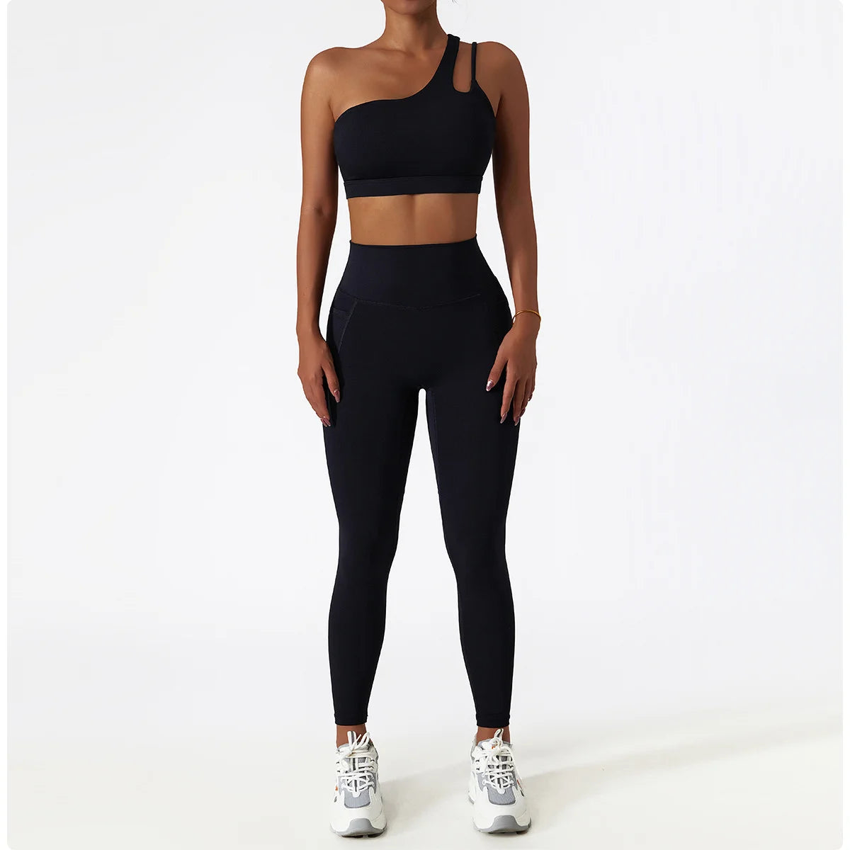 KiKis black one shoulder sports bra and leggings set worn by model with white sneakers