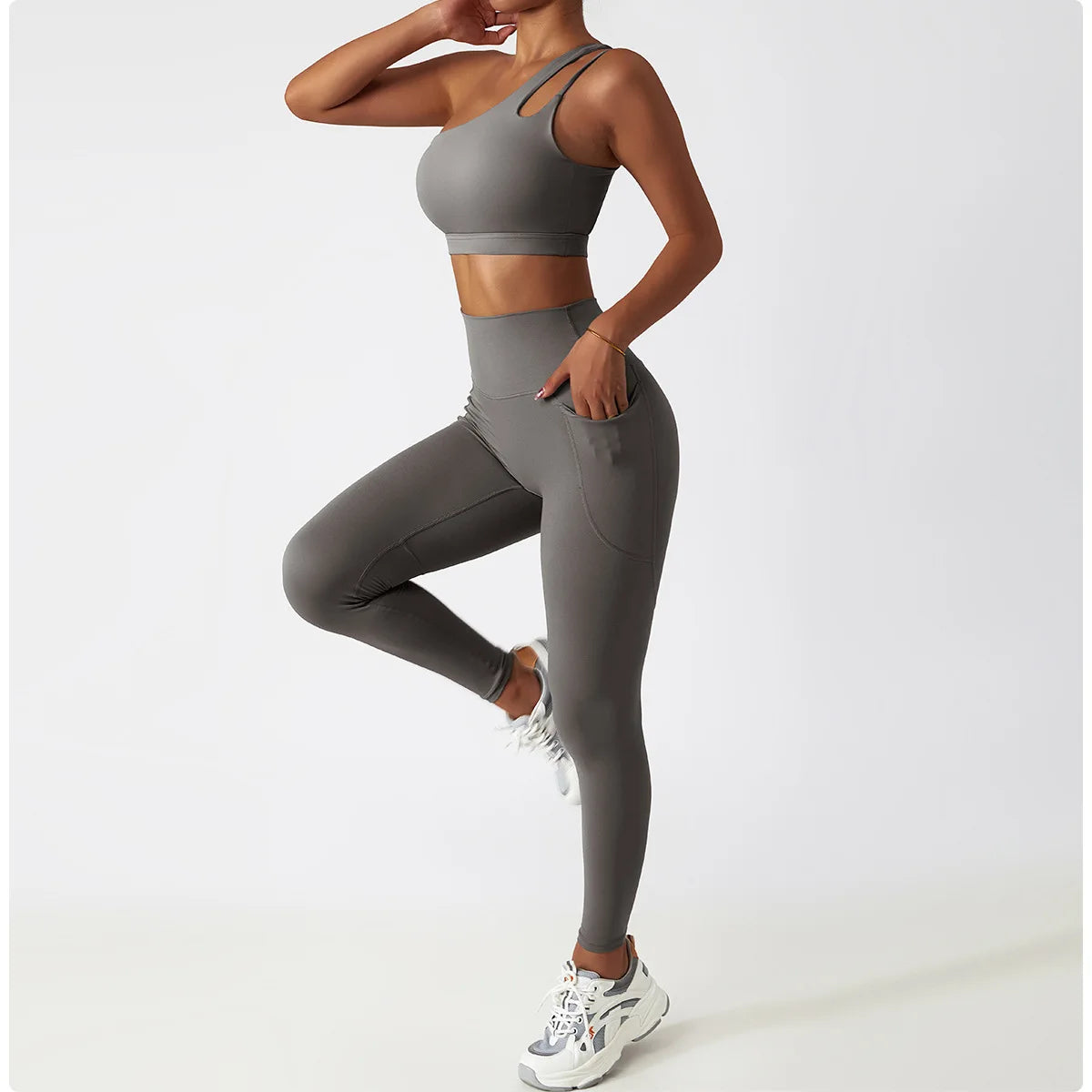 KiKis one shoulder sports bra and leggings set in gray with high-waist leggings and pocket detail