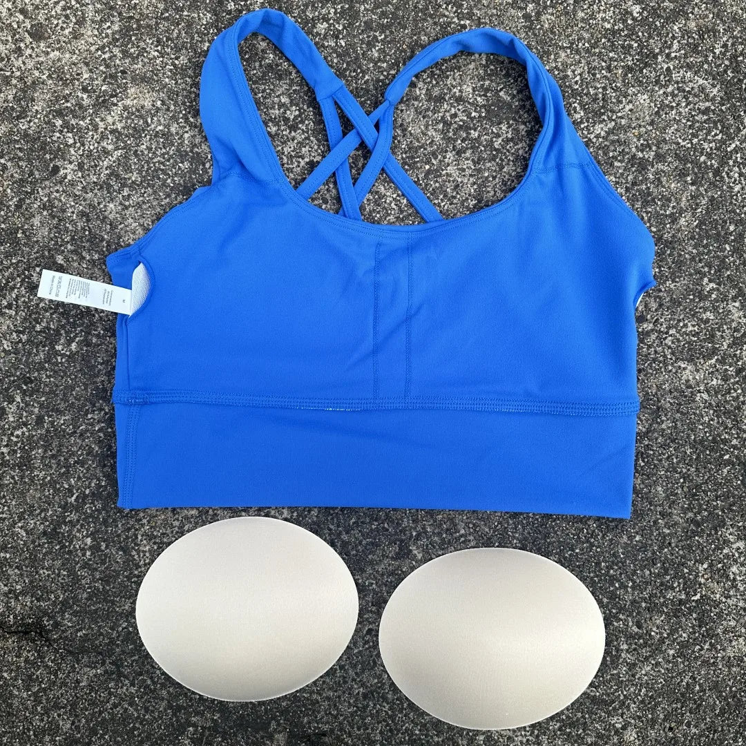 KiKis blue cross back sports bra for women with removable padding laid on concrete