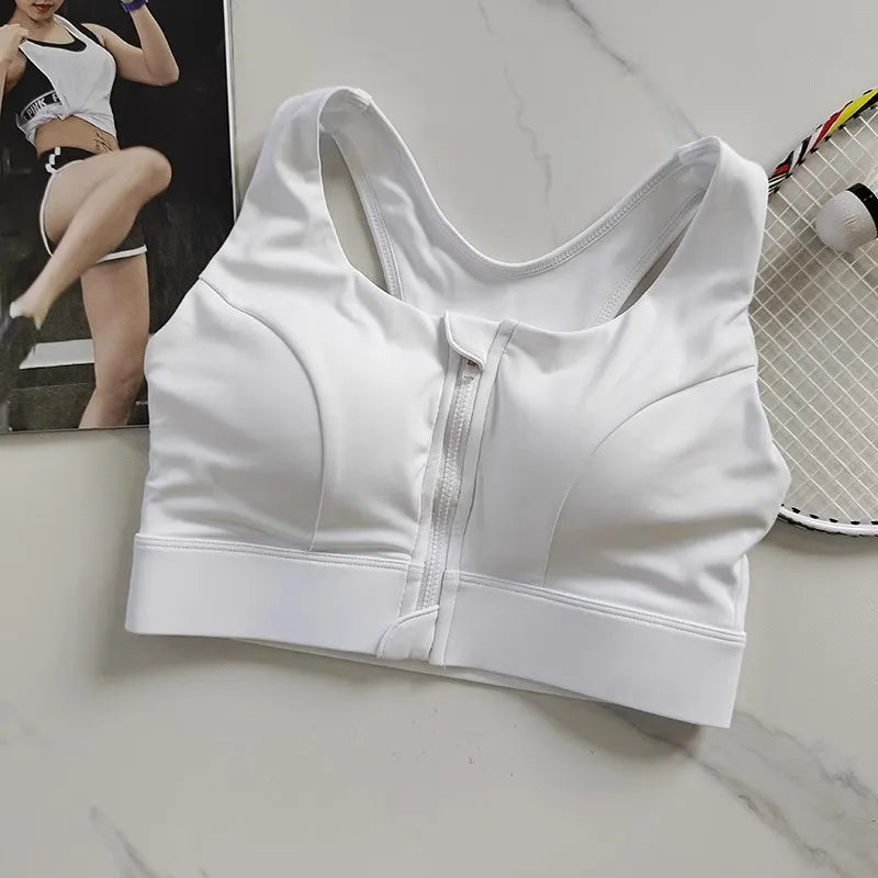 KiKis white high impact front zipper sports bra laid flat with a tennis racket in the background