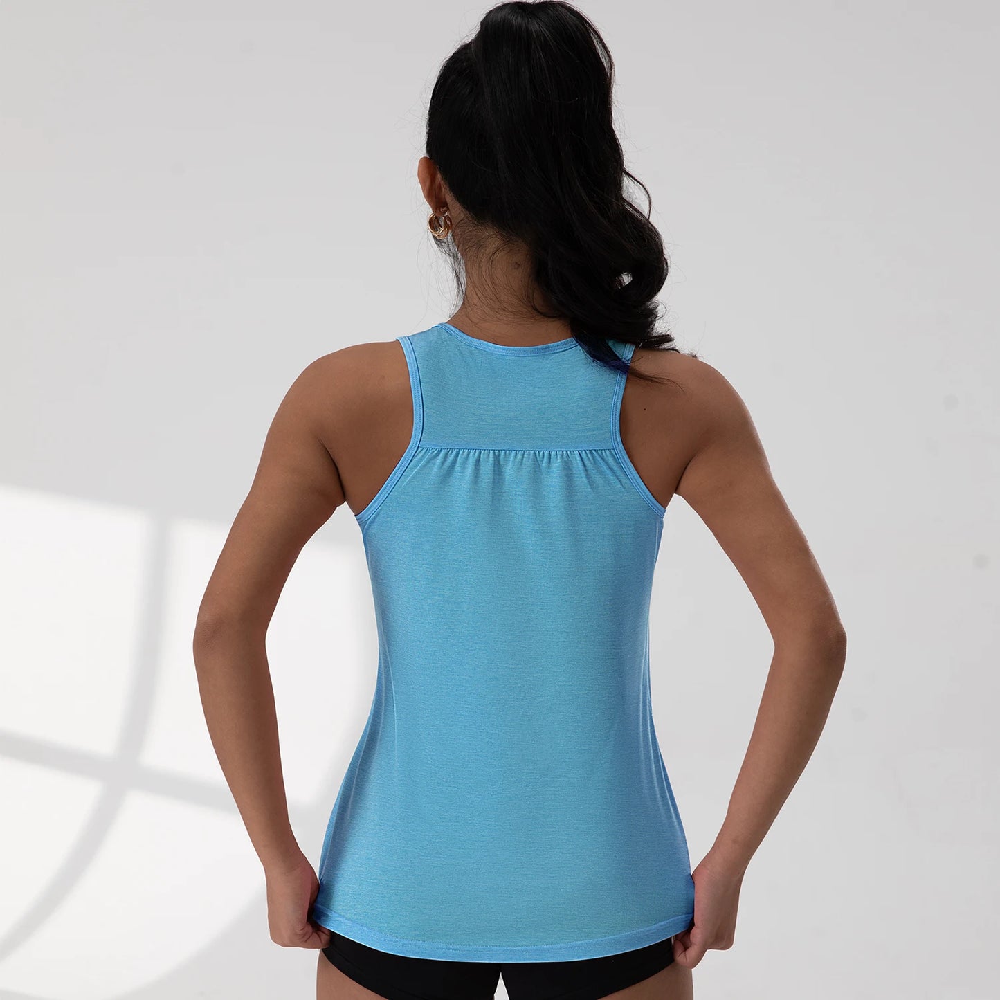 KiKis blue round neck sleeveless gym top worn by woman shown from the back