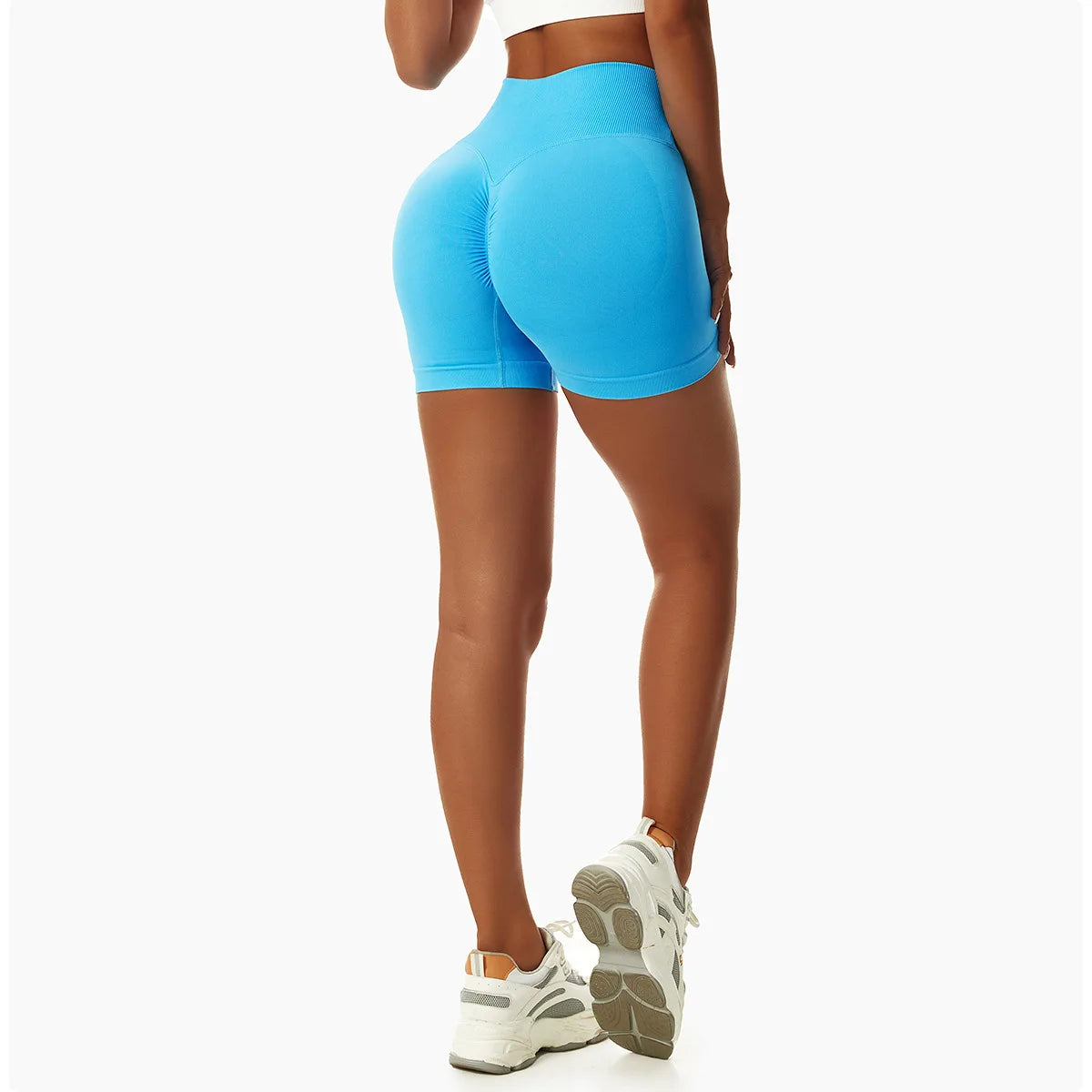 Woman wearing blue high waist seamless yoga shorts showing back view with white sneakers