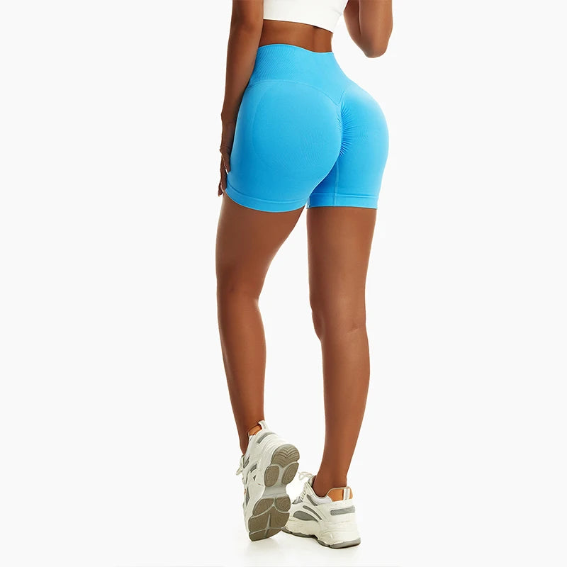 Woman wearing bright blue high waist seamless yoga shorts and white sneakers standing with back facing camera