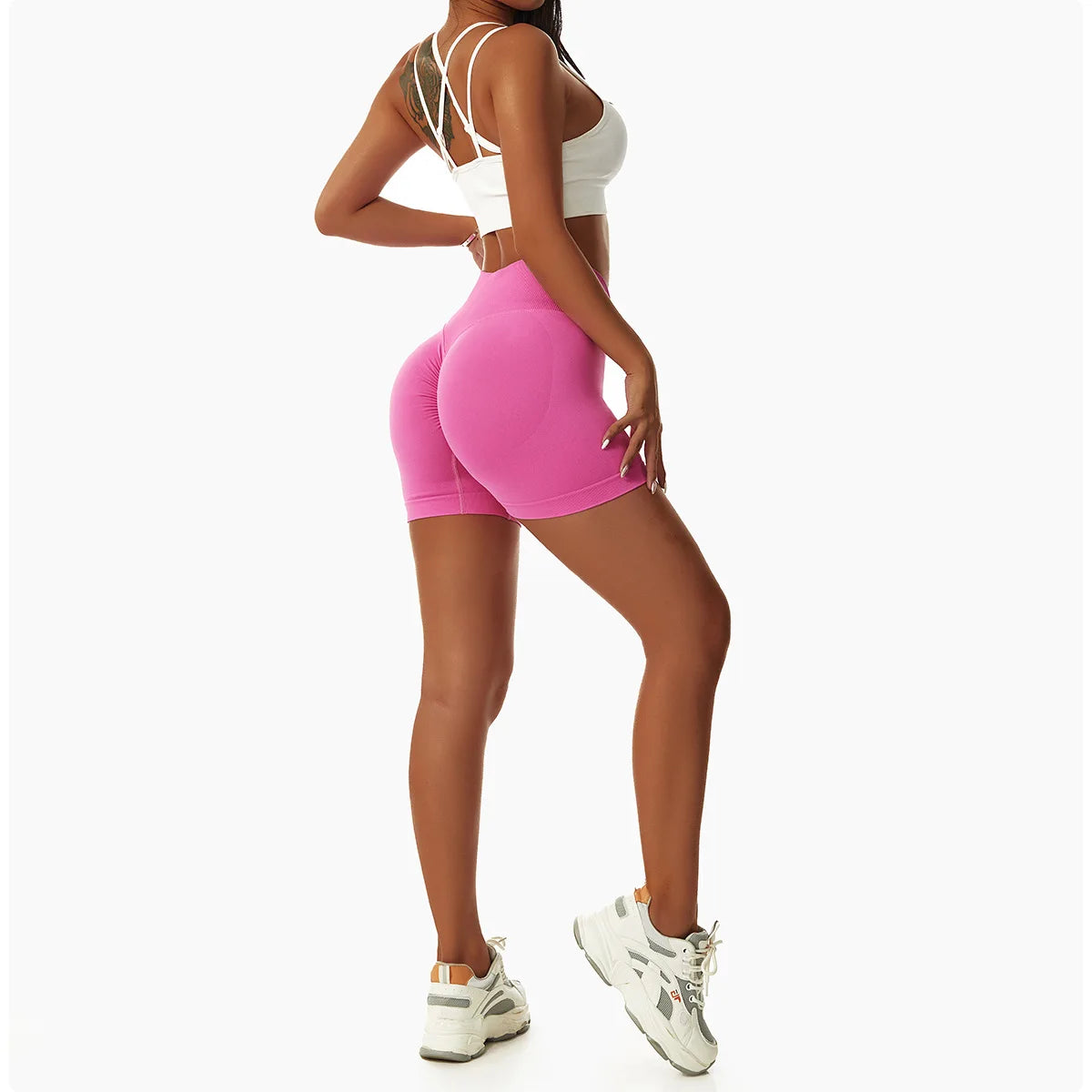 Woman wearing KiKis pink high waist seamless yoga shorts and white sports bra with athletic shoes