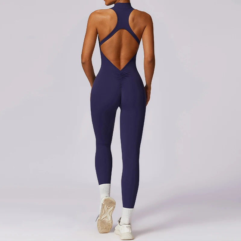 Back view of a woman wearing a navy blue v back one-piece yoga suit with white sneakers