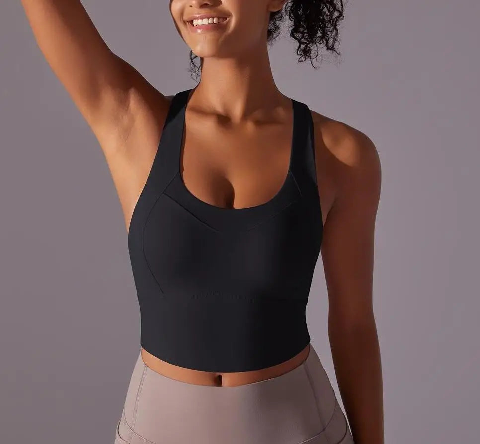 KiKis seamless crossback sports bra for women in black worn by smiling woman with raised arm
