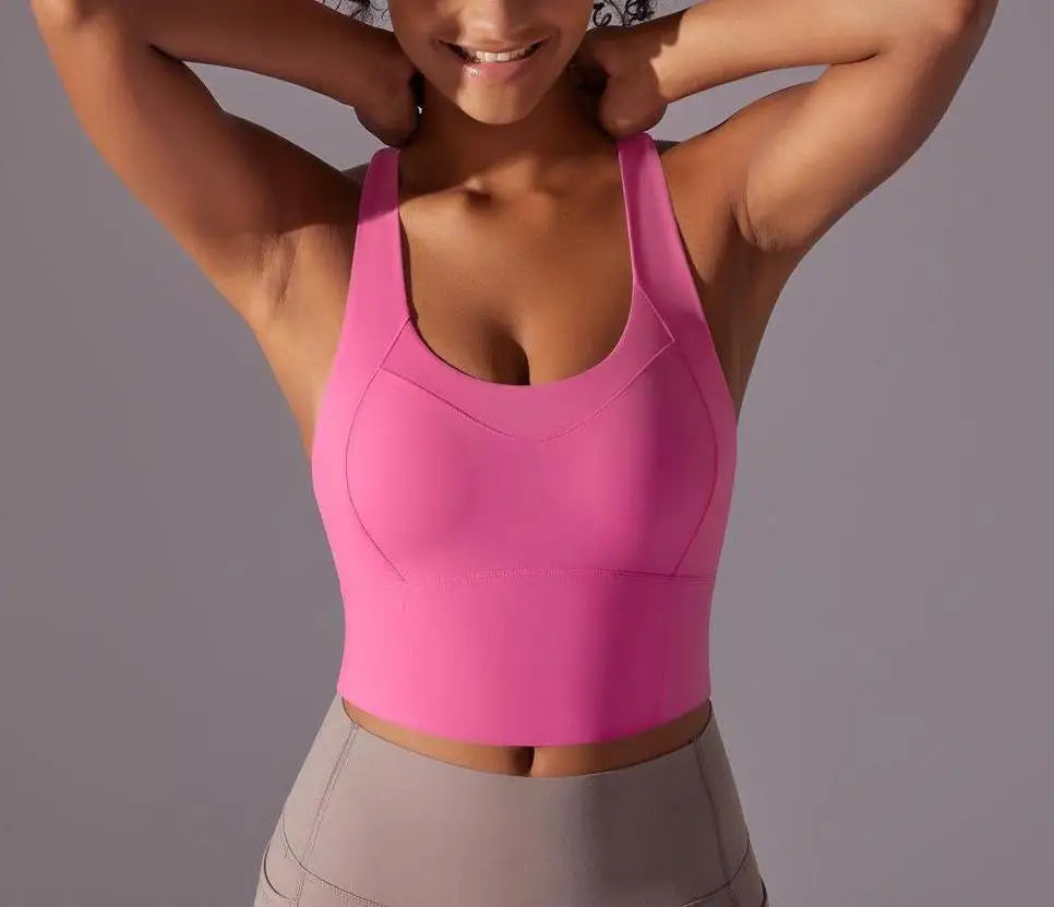 KiKis seamless crossback sports bra for women in bright pink shown on a smiling model