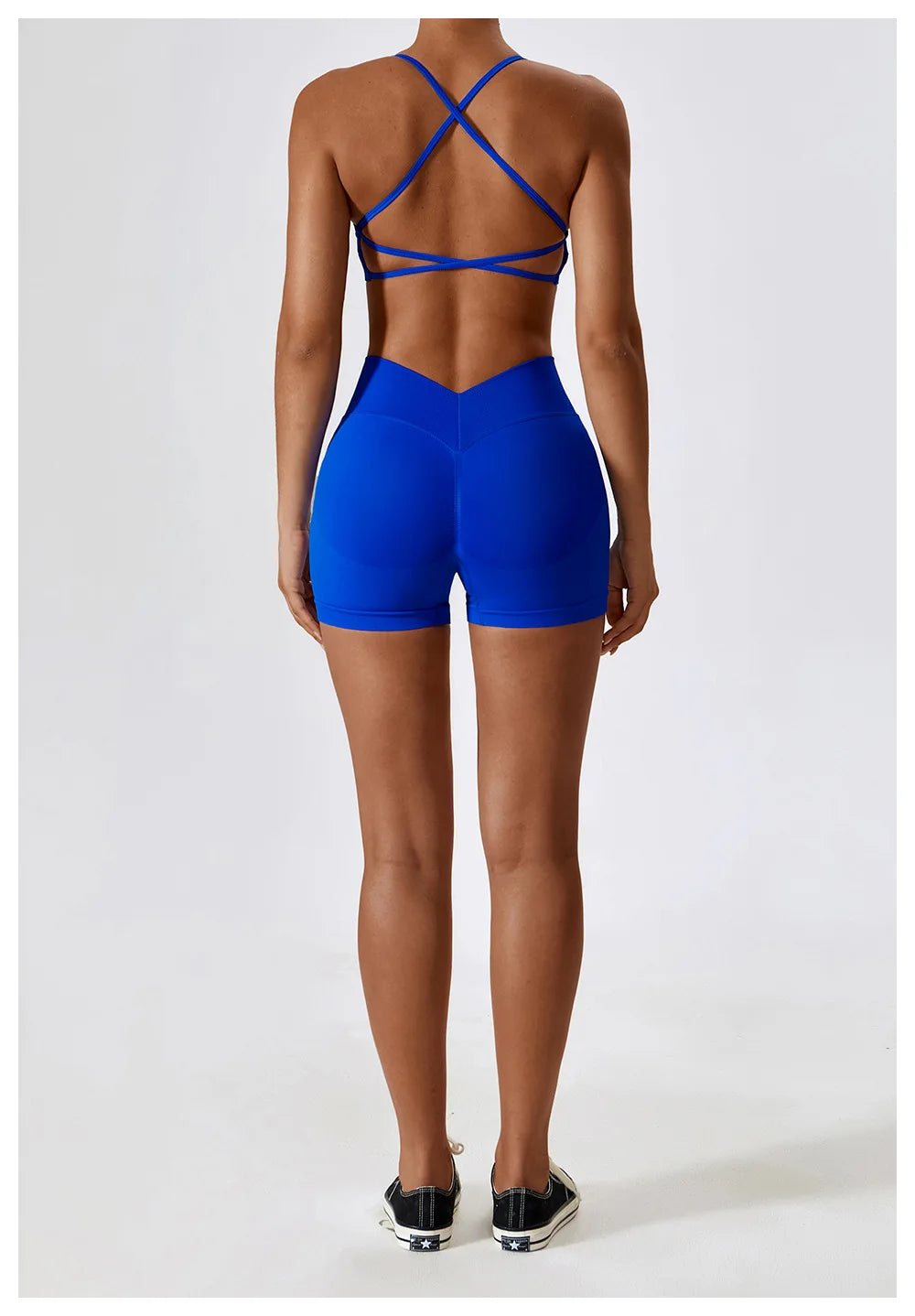 Back view of woman wearing bright blue seamless scrunch butt gym shorts with crisscross sports bra