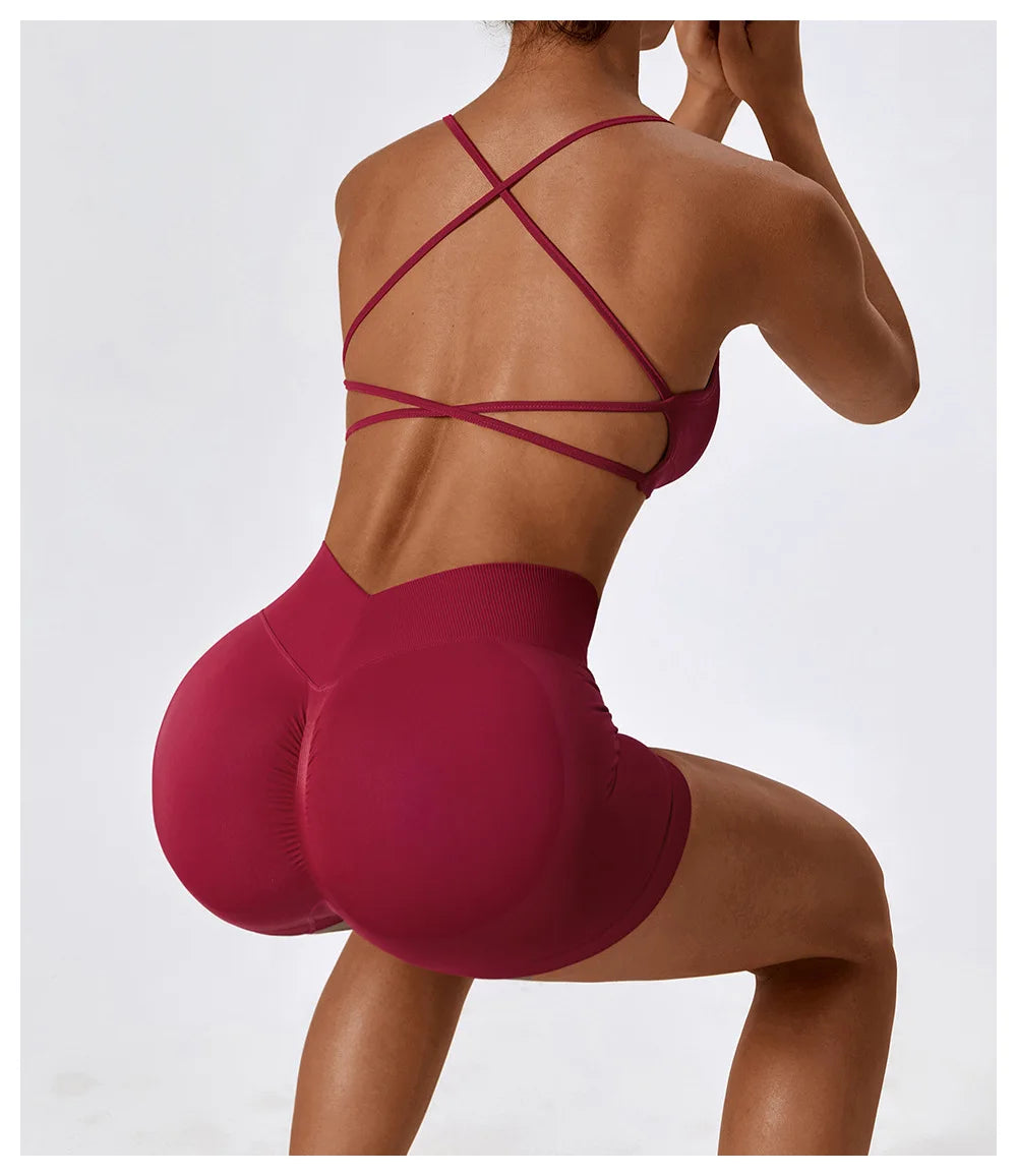 Woman wearing burgundy seamless scrunch butt gym shorts with crisscross sports bra straps