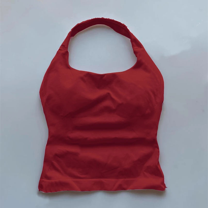Red seamless backless sports tank top with halter neck design laid flat on a white surface