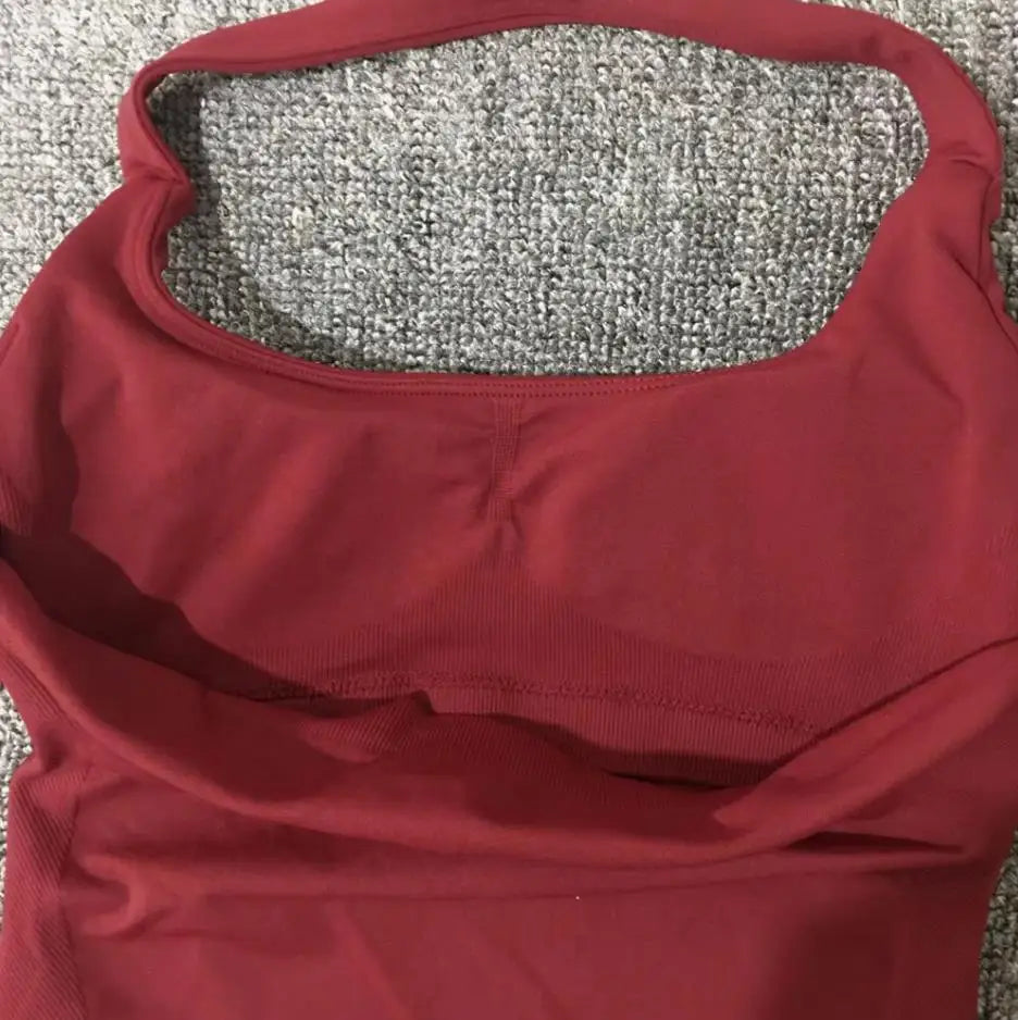 KiKis seamless backless sports tank top in red lying flat on gray carpet background