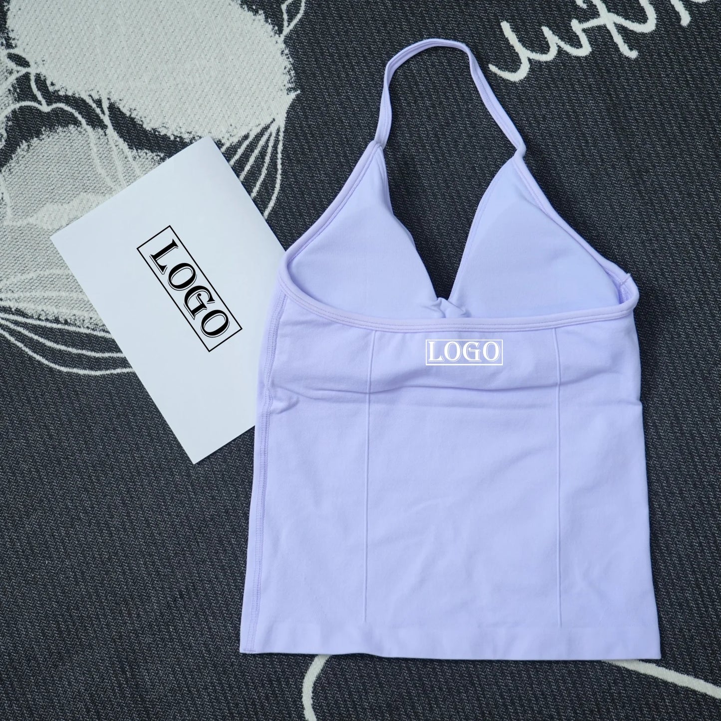 Light purple seamless yoga sports bra with thin straps laid flat on a textured surface