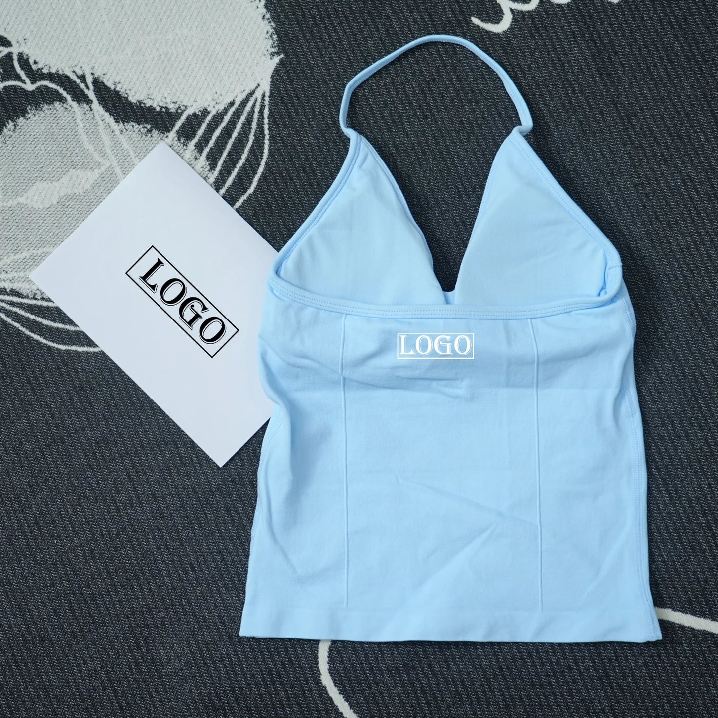 Light blue seamless yoga sports bra with halter neck design laid flat on dark patterned surface