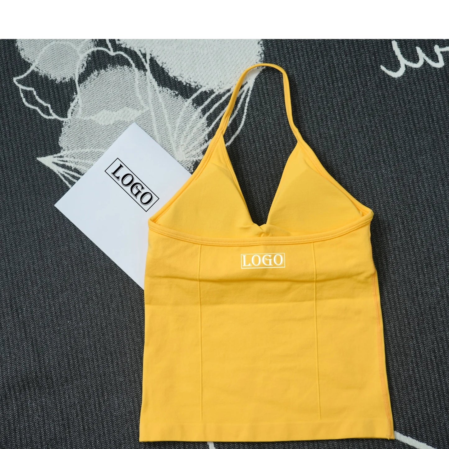 KiKis yellow seamless yoga sports bra with thin straps and V-neck design laid flat on a patterned surface