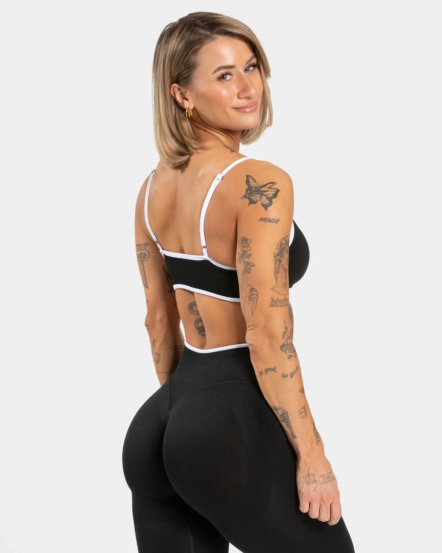 KiKis shockproof yoga bra outdoor fitness worn by tattooed woman with black leggings on white background