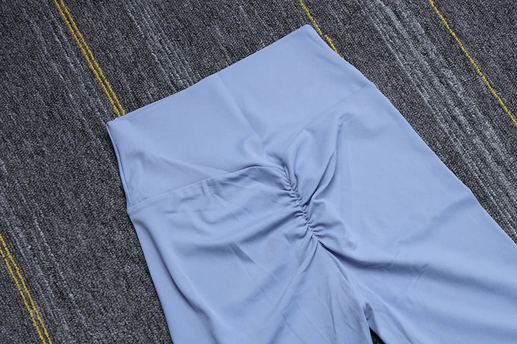 Light blue Womens Seamless Yoga pants by SOISOU with ruched front detail laid flat on textured surface