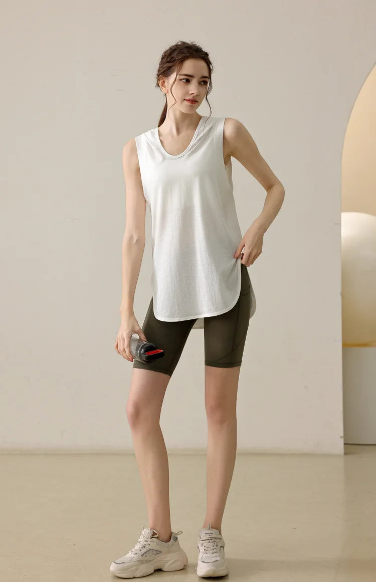 KiKis white summer sleeveless workout hoodie worn by woman with olive biker shorts and sneakers