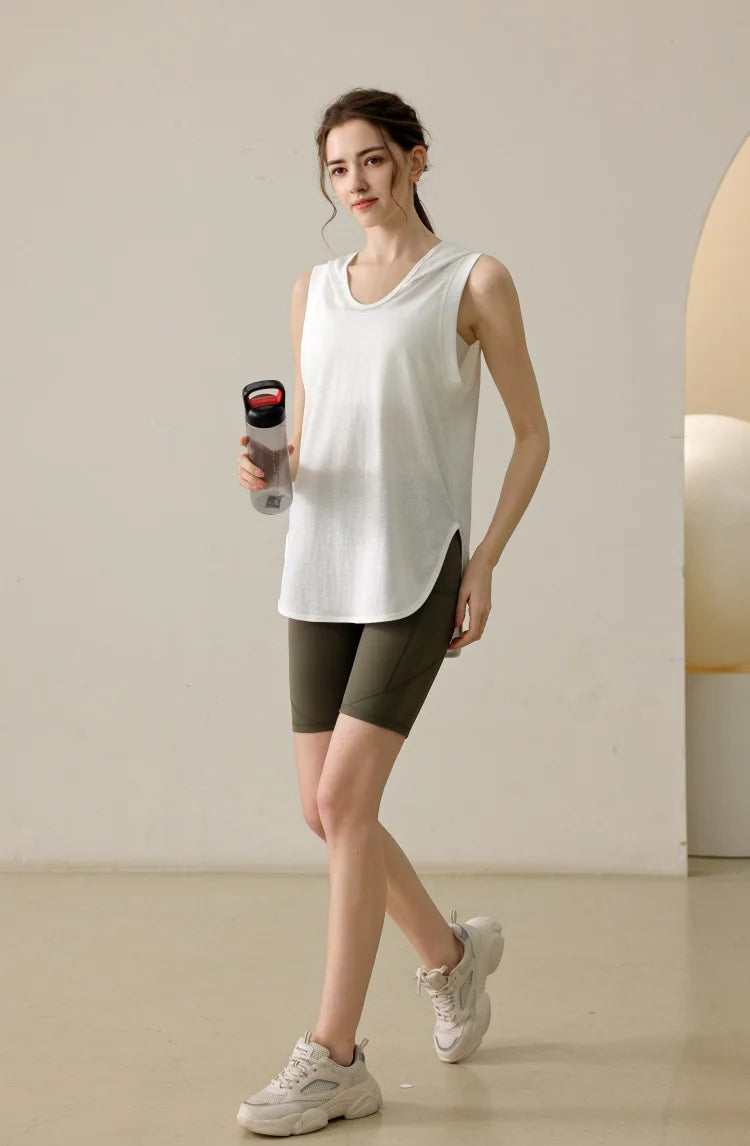 KiKis summer sleeveless workout hoodie in white worn by woman with green shorts holding water bottle