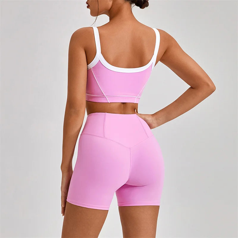 Back view of a woman wearing women's nude fitness shorts set in pink with white trim from KiKis