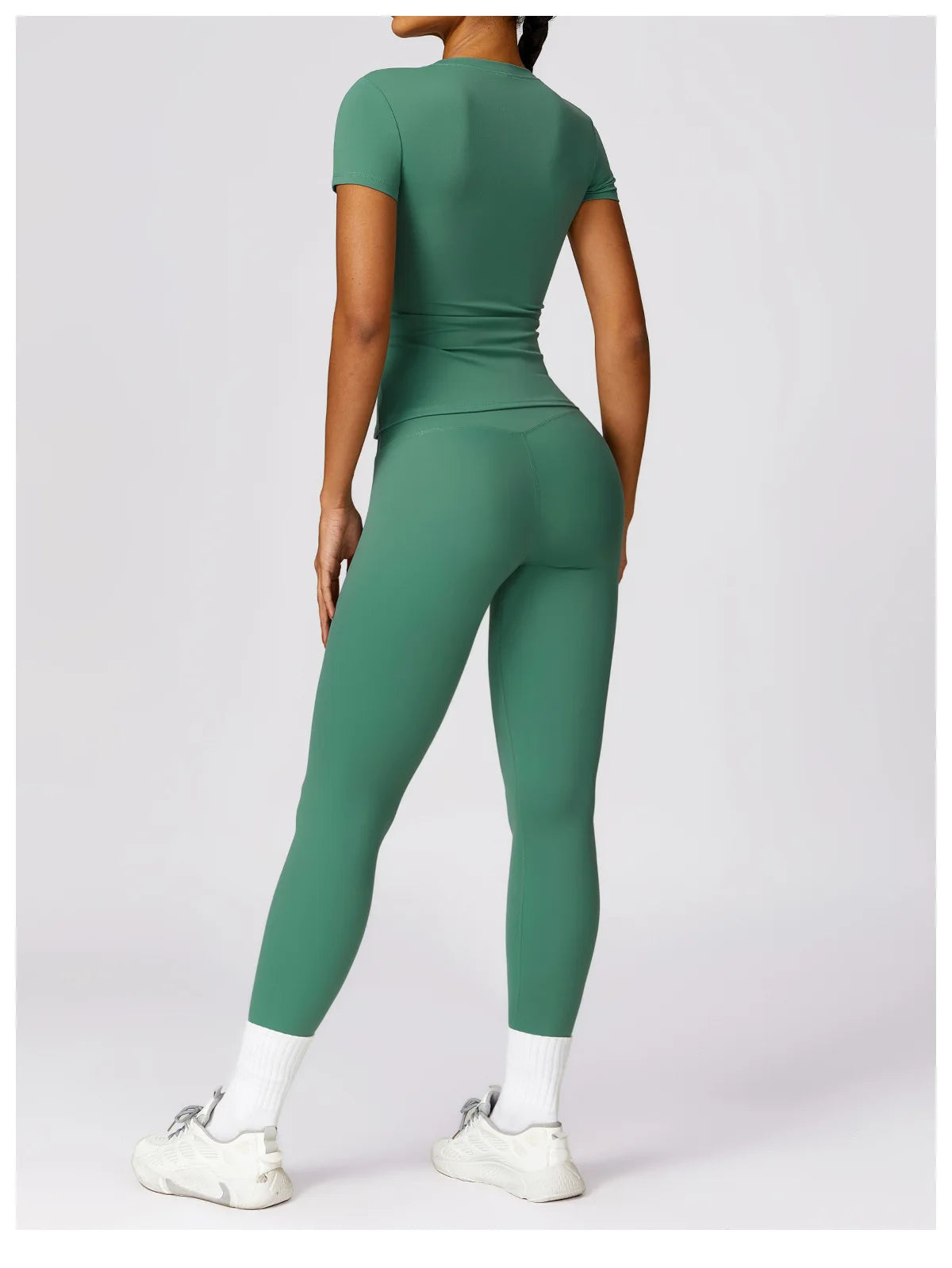Woman wearing green seamless yoga top for women and matching leggings with white sneakers