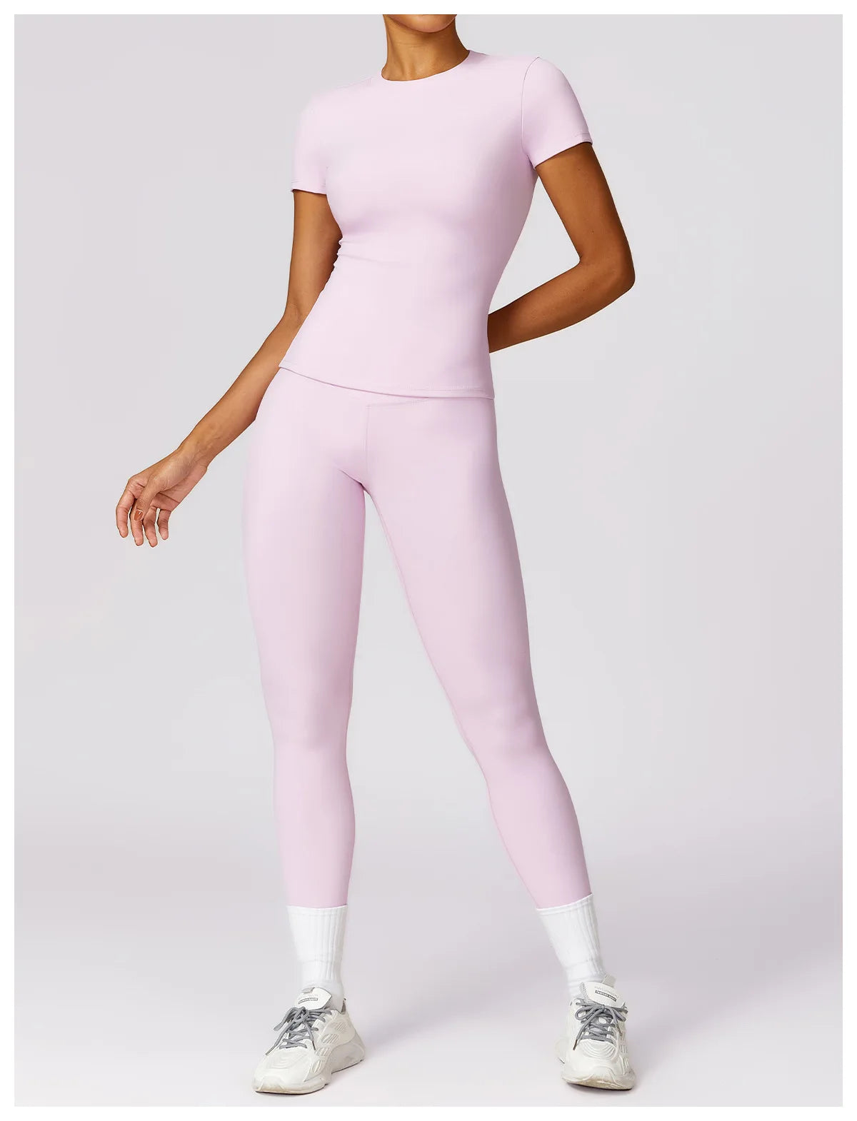 Light pink seamless yoga top for women worn with matching leggings and white sneakers