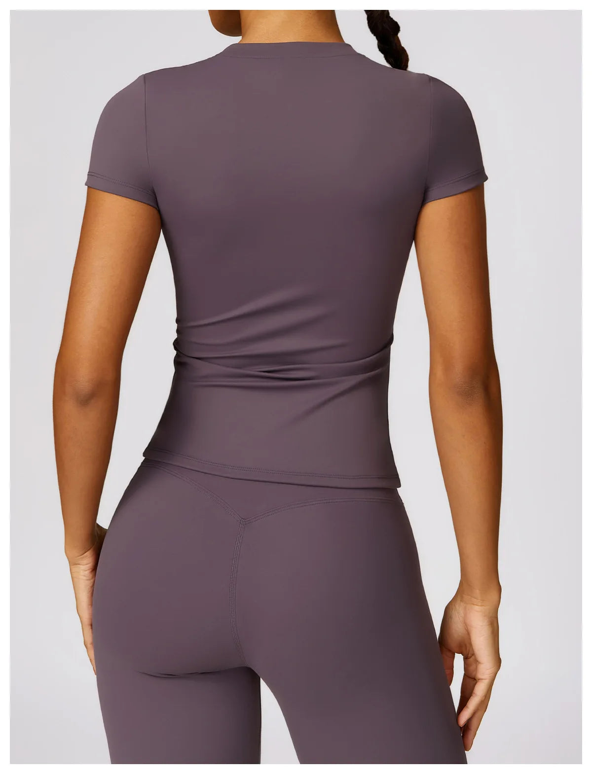 Back view of a woman wearing a purple seamless yoga top for women and matching leggings by KiKis