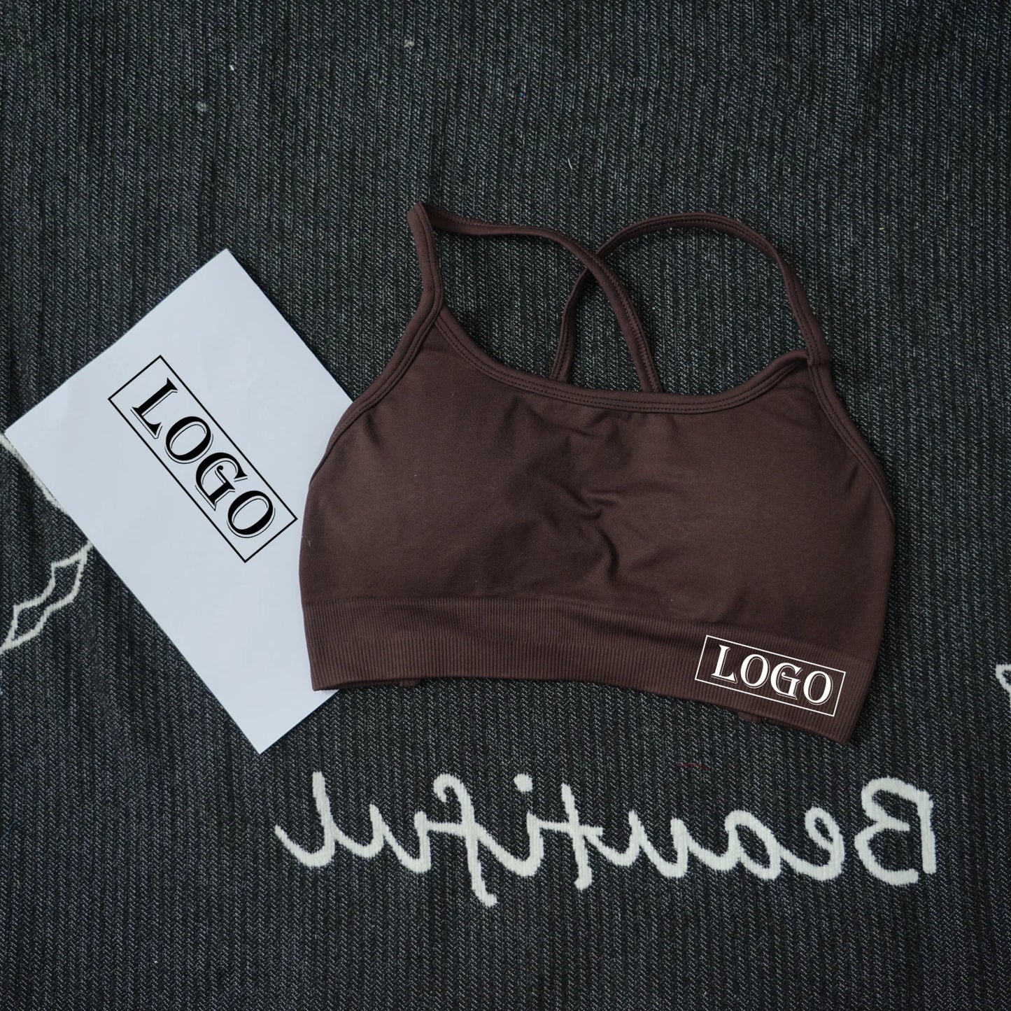 KiKis brown women's seamless sports bra with thin straps laid on textured black surface